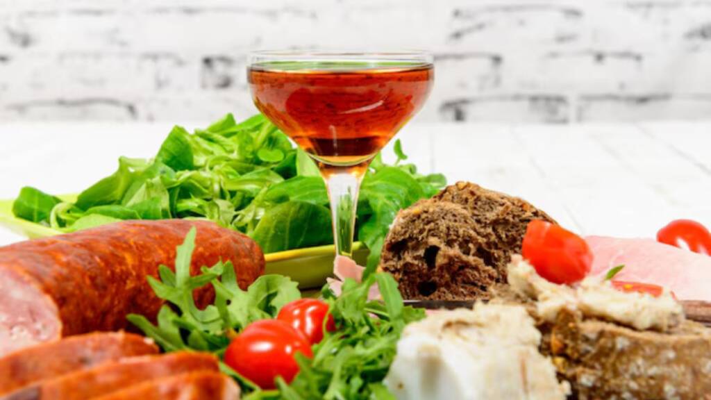 Glass of vodka served with greens, sausage, and bread