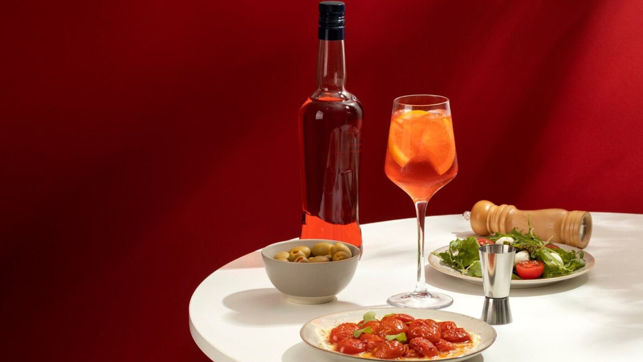 Liquor bottle and cocktail with appetizers on a table.