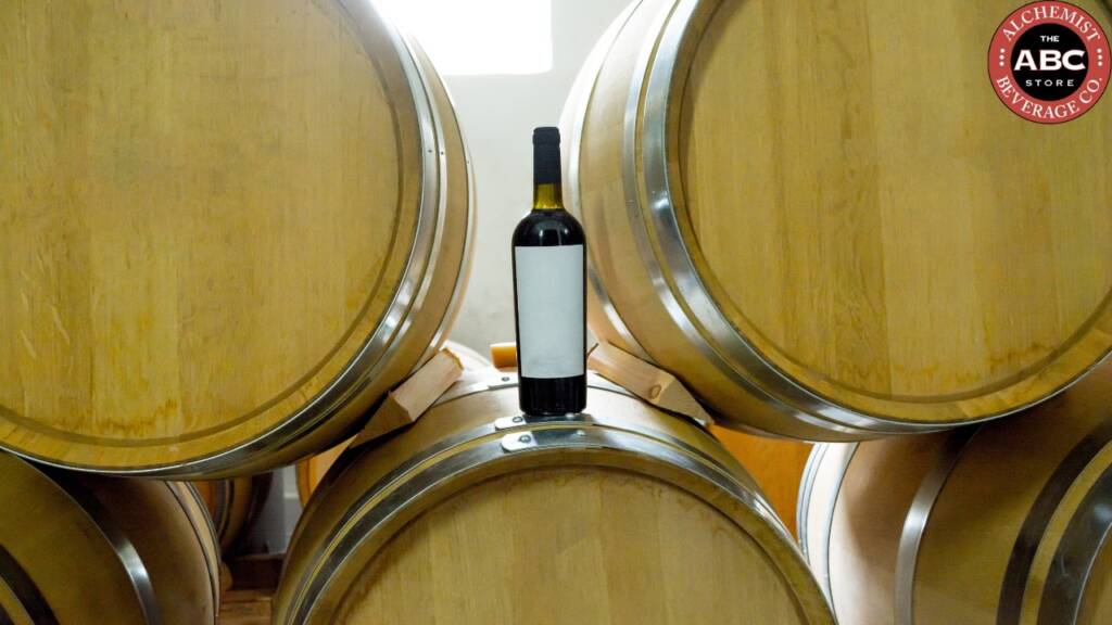 Wine bottle placed on stacked oak barrels in aging cellar