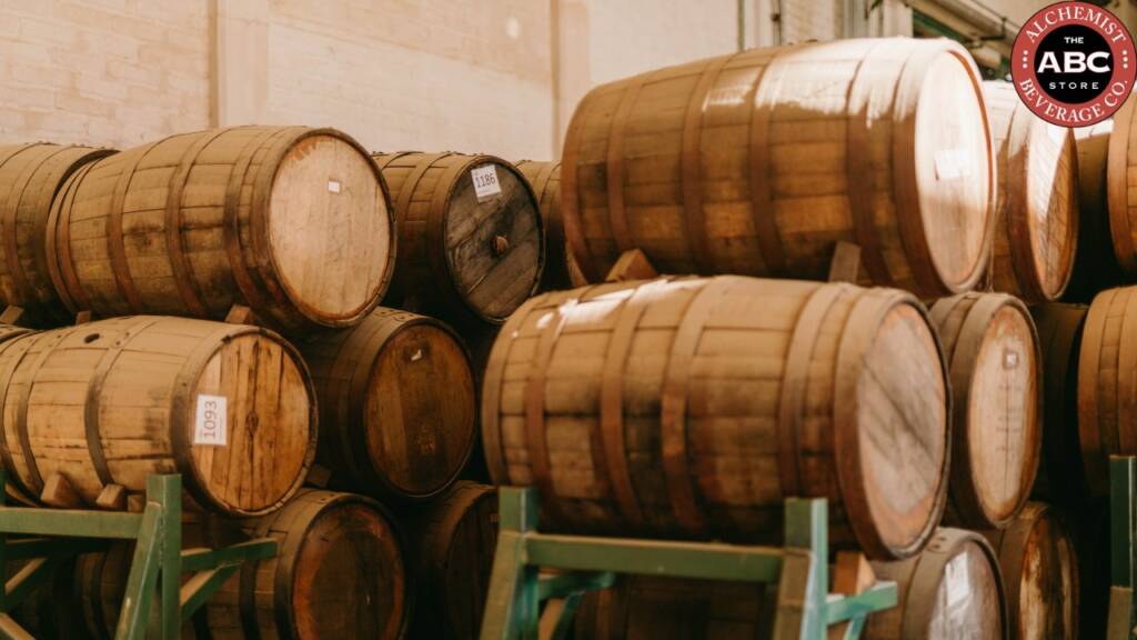Stacked wooden barrels used for aging liquor inside a distillery.